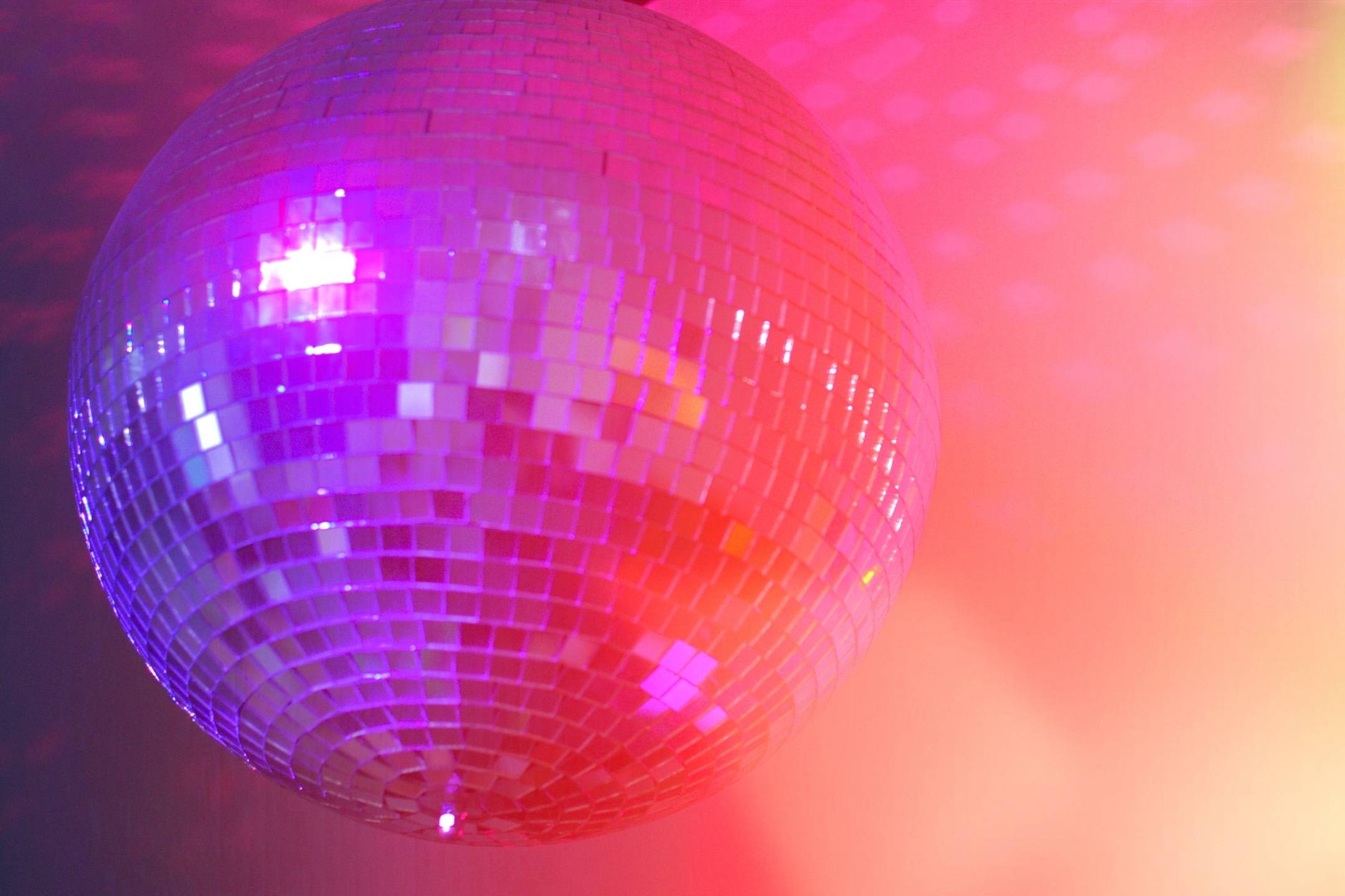 A close-up of a  ball reflecting pink and purple light, with a colorful gradient background.